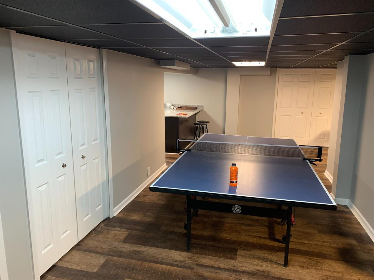 Multi-Use Basement Remodel with Ping Pong Zone – Pleasant Ridge, MI Spacious finished basement with recessed lighting, dark ceiling tiles, and a dedicated ping pong table area – remodeled in Pleasant Ridge, Michigan