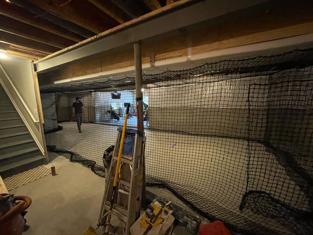 Basement Softball Training Area Under Construction – Oakland County, MI Basement addition designed for indoor softball training with wall netting, open framing, and protective barriers – sports-focused renovation project in Oakland County, Michigan