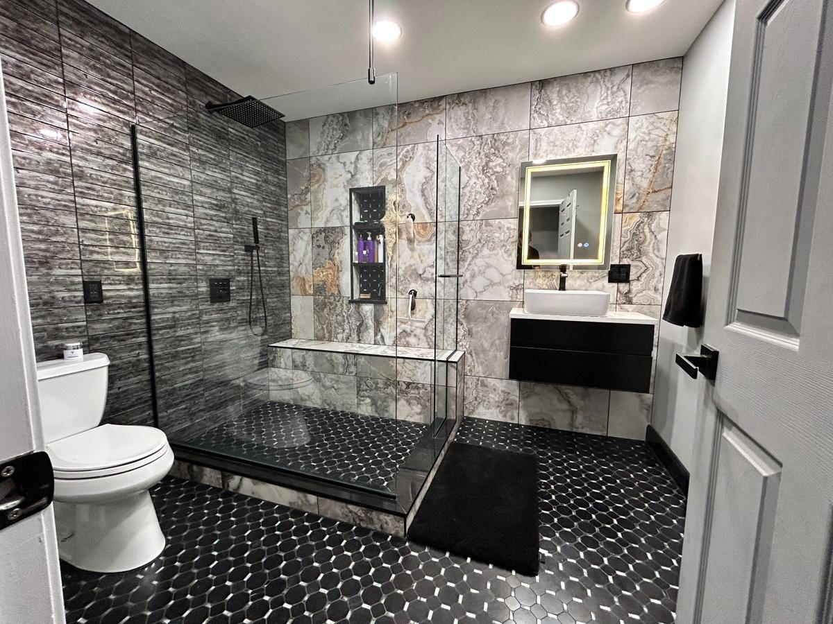 Black and Marble Spa-Inspired Bathroom Renovation – Royal Oak, MI Luxury spa-style bathroom with black hex tile floor, marble wall tile, and glass-enclosed shower – completed renovation in Royal Oak, Michigan