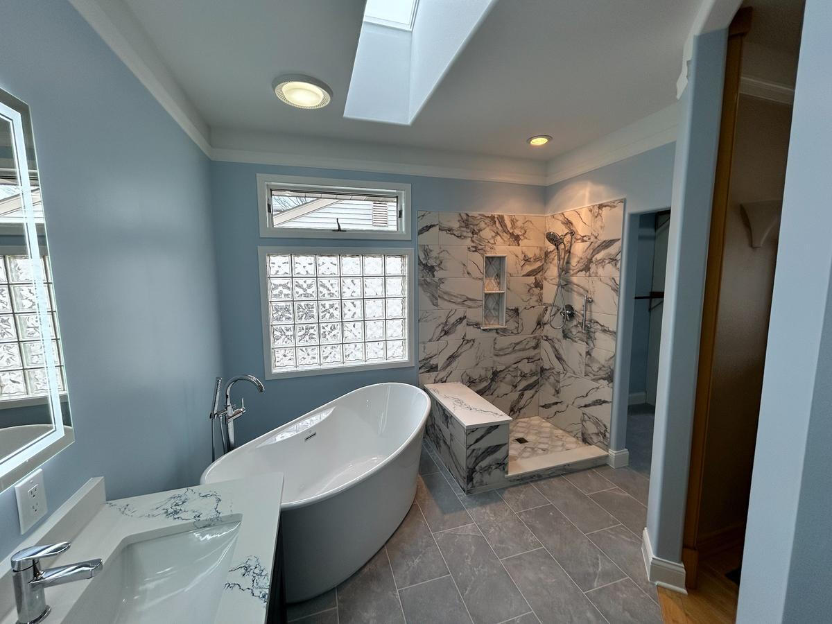 Elegant bathroom remodel featuring soaker tub and marble walk-in shower with bench – Birmingham, MI