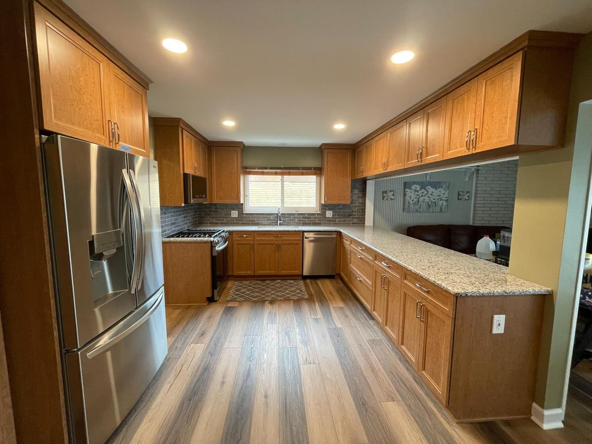 Howell Kitchen Makeover Featuring Natural Wood Finishes L-shaped kitchen featuring natural wood cabinets and laminate flooring – Troy, MI home renovation