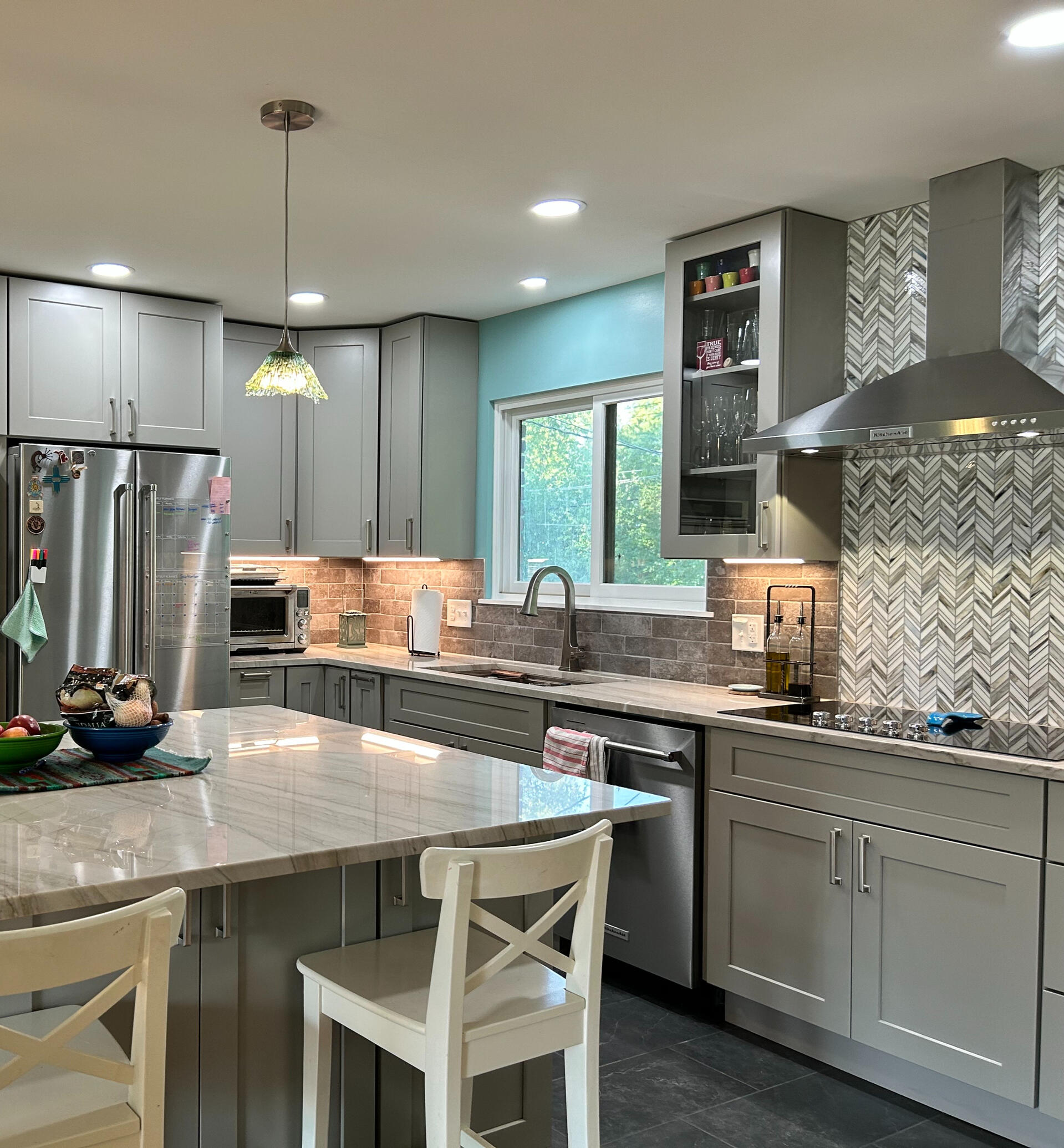 High-End Kitchen Renovation with Custom Backsplash – Michigan Modern kitchen remodel with patterned tile backsplash, stainless steel range hood, pendant lighting, and island seating – upscale project in Birmingham, Michigan